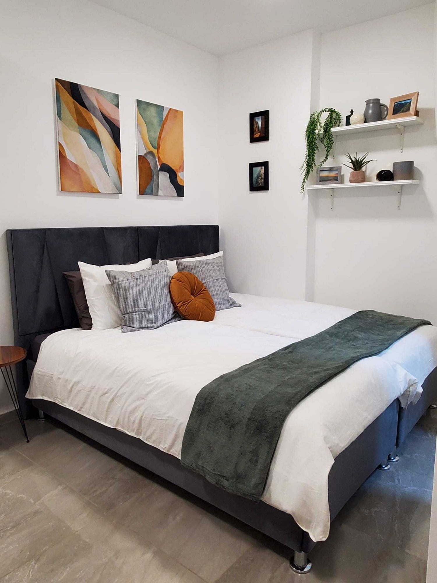 Bedroom with crisp white bedding, a green throw and layered pillows