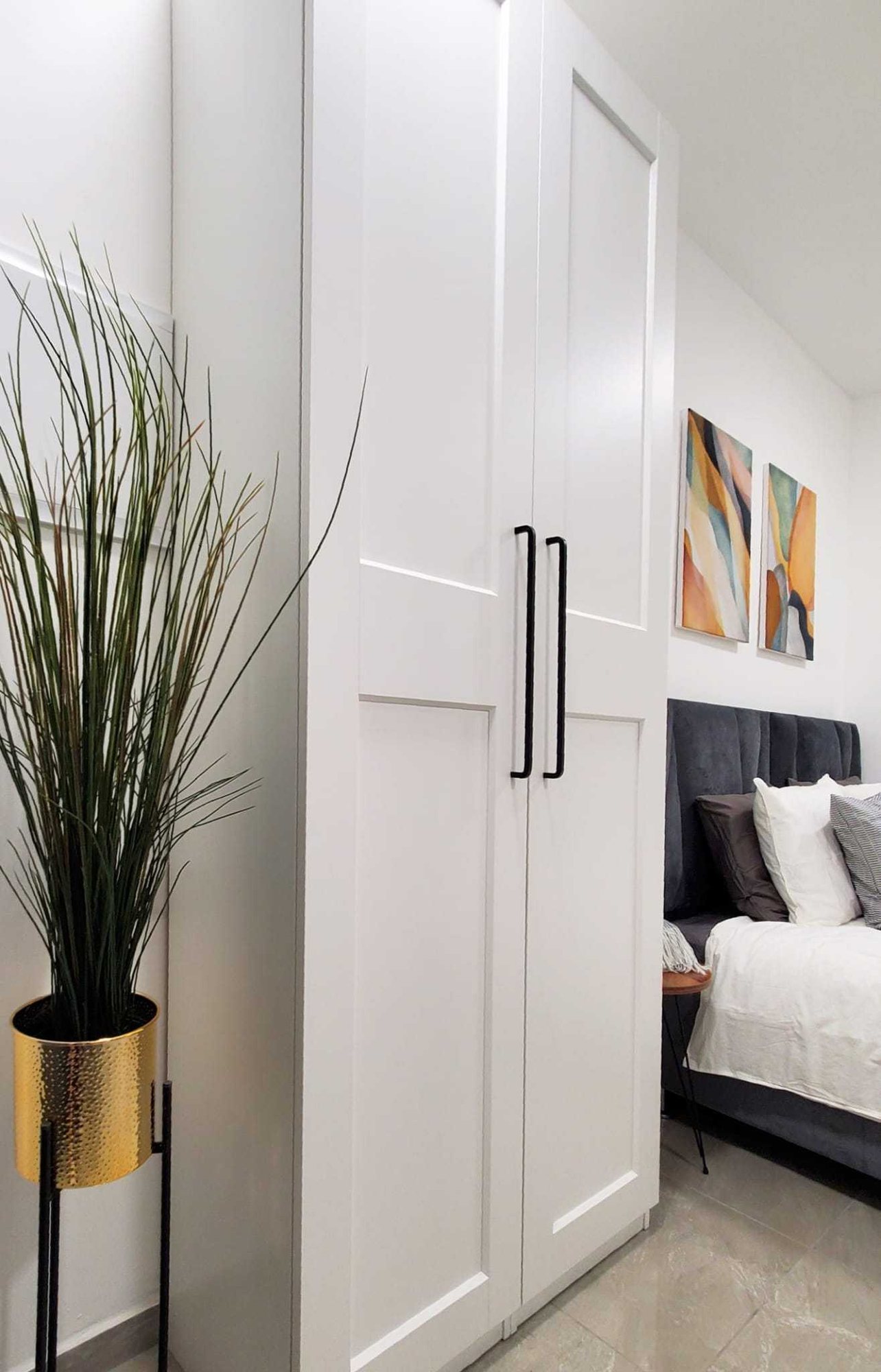 Large white wardrobe beside the bed